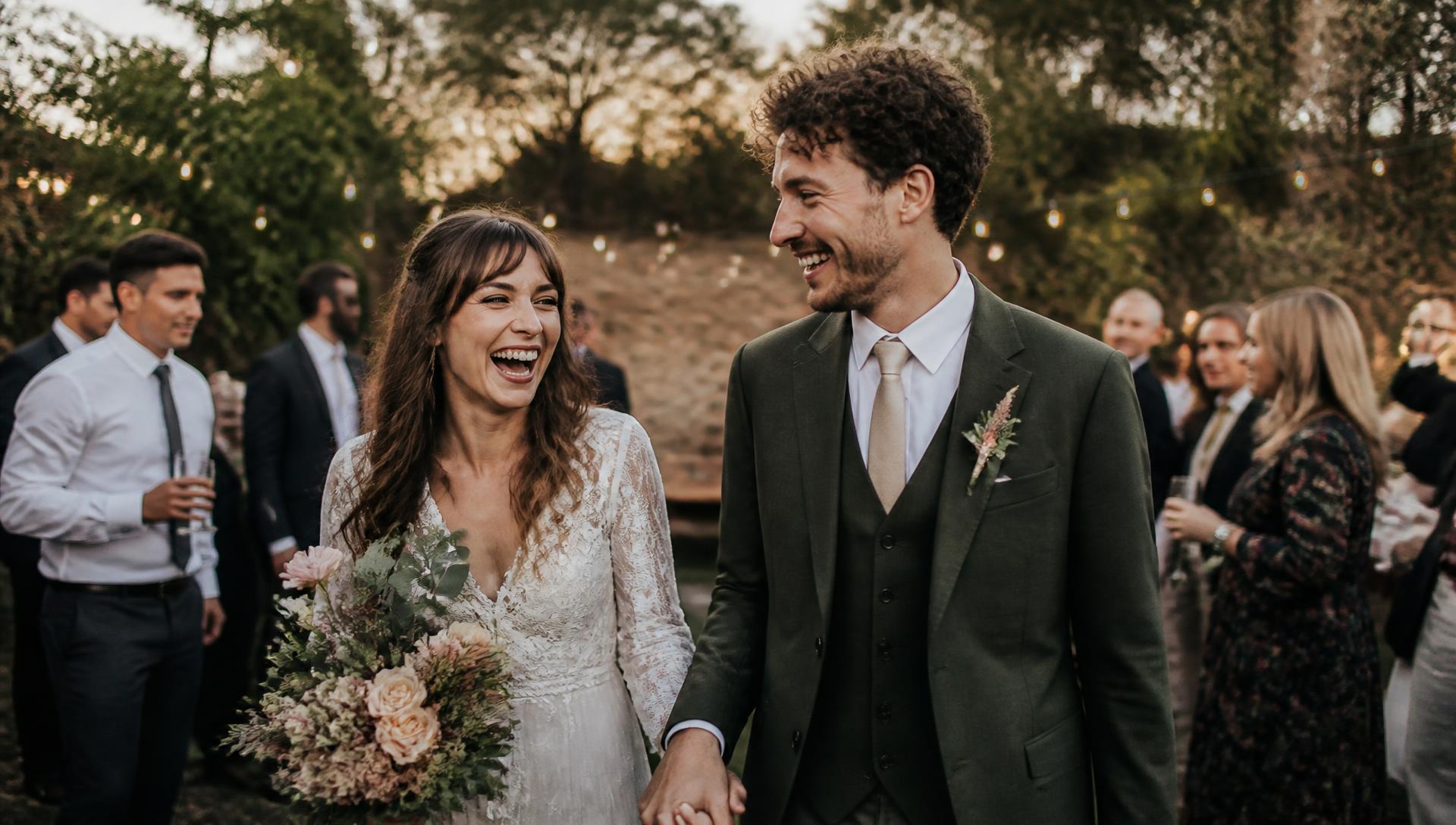 A couple laughing together at their outdoor wedding celebration