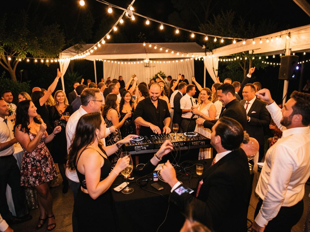 Guests dancing at a wedding reception under string lights